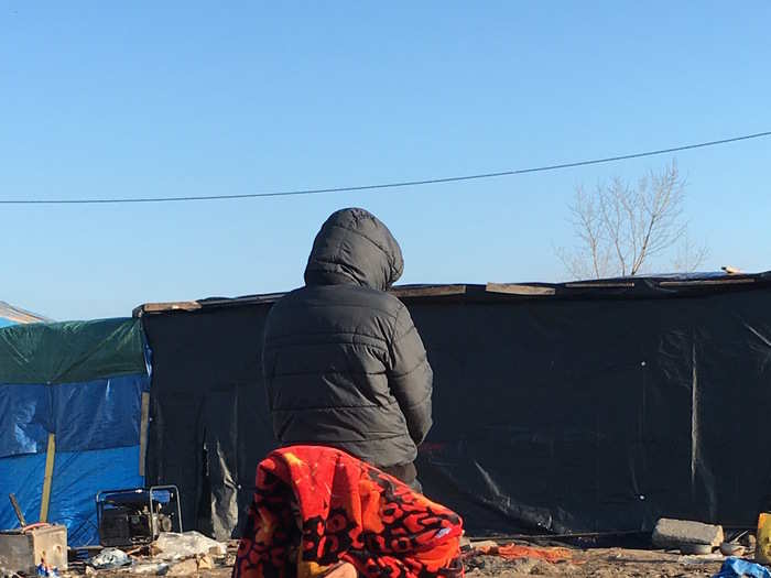 Two of the three men who were just woken up by the police as they were sleeping in their shelter pose for a picture while hiding their faces.