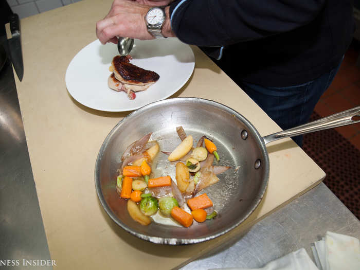 After the chicken is cooked in the circulator, it comes out and is plunged in ice water. Next, a mix of caramelized apples and onions is added with Brussels sprouts, carrots, and butternut squash.