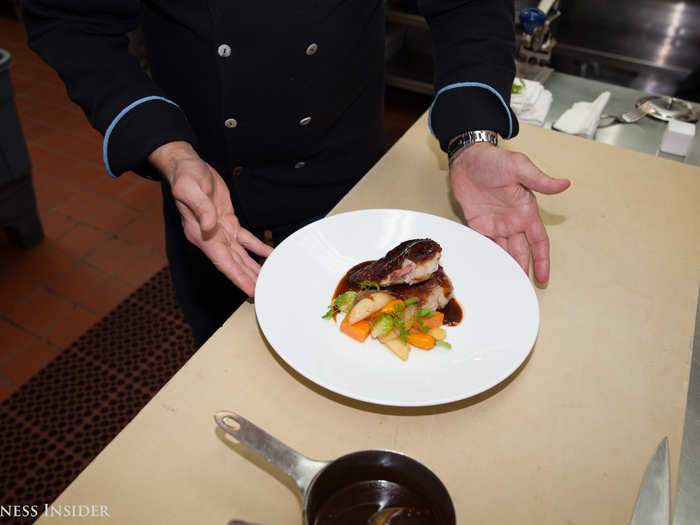 After placing the chicken and vegetables on the plate, Portale garnishes it with a few herbs. At the Singapore Airline packing facilities, all hot ingredients are packed together, while cold ingredients are packed separately so that the staff can make final touches like this during the flight.