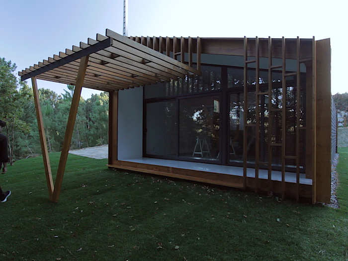 A wooden pergola shades the sleek all-glass entrance area.