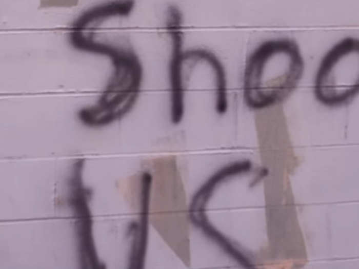 ...In one shot, graffiti on a wall says, "Stop shooting us," pointing to recent cases in which black men were killed by police.