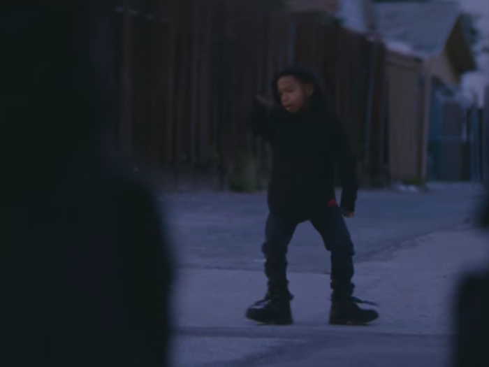 Toward the end of the video, we see a black boy dancing in front of a line of police.