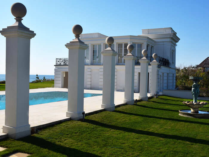 Manicured lawns and a contemporary pool overlook the ocean beyond.