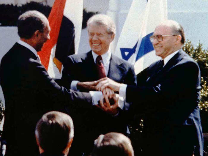 3. Anwar Sadat, Menachem Begin, and Jimmy Carter engage in a three way handshake to mark the end of the signing of the Israeli-Egyptian peace treaty.