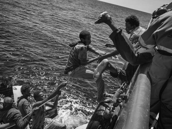 Contemporary Issues Stories, 2nd prize: Francesco Zizola, Italy — Migrants climb on board of a rescue ship by Doctors without Borders to escape their sinking rubber dinghy. Strait of Sicily, Mediterranean Sea, 21 August 2015.