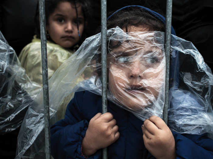 People Singles, 1st prize: Matic Zorman, Slovenia — A child is covered with a raincoat while she waits in line to register at a refugee camp in Pres?evo, Serbia, 07 October 2015.