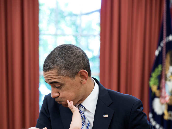 Obama puffs out his cheeks to amuse an infant visitor to the Oval Office.