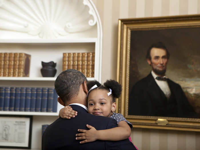 Abraham Lincoln watches in approval as the president and a young girl share a hug in the Oval Office.