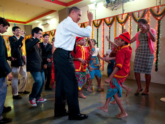 First Lady Michelle Obama persuades her husband to join in the dancing in Mumbai, India.