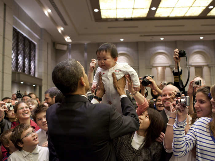 The president hoists a baby into the air during a visit to Japan.