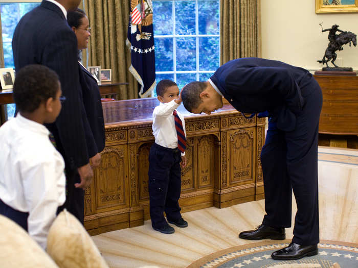 A young boy reaches up to compare the president