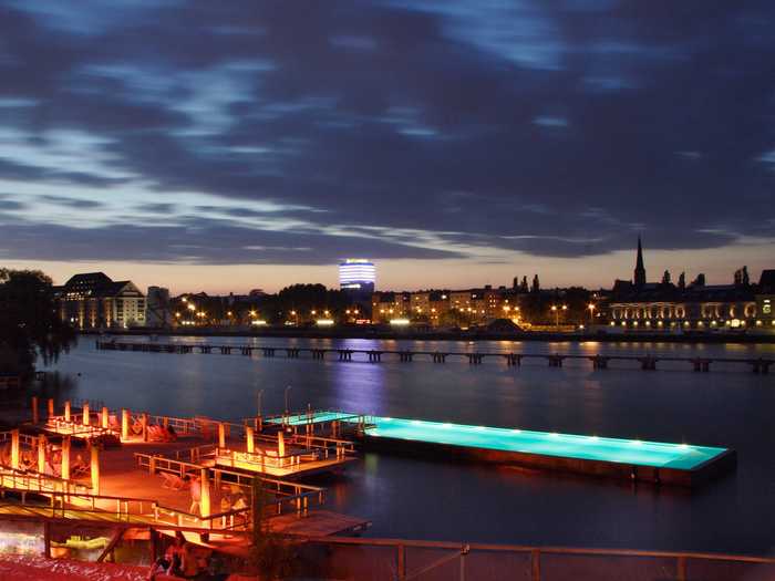 Berlin’s Arena Badeschiff floats inside the Spree River and offers panoramic views of the city, food, drinks, music, and lounge chairs for relaxing.