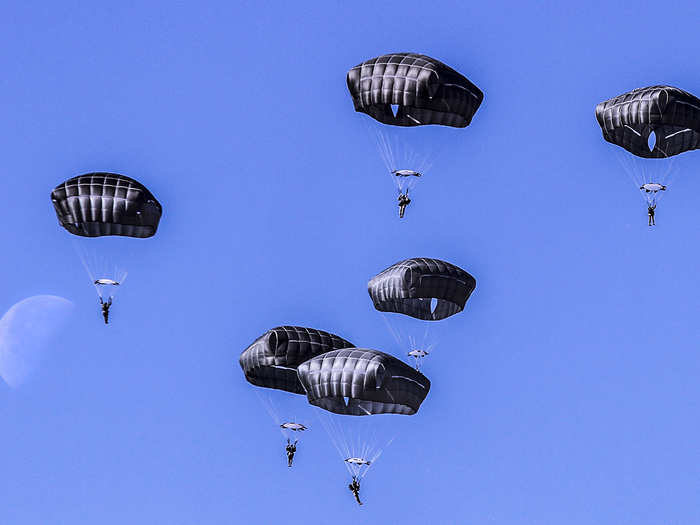 Paratroopers assigned to 3rd Brigade Combat Team, 82nd Airborne Division descend toward Holland Drop Zone against the backdrop of a crystal clear sky and last quarter moon during an airborne proficiency jump.