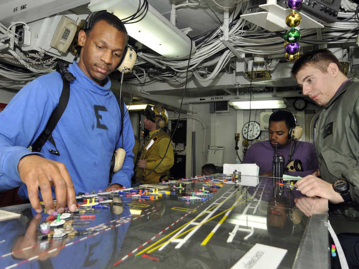 Airman position model aircraft on a planning board in the flight deck control center aboard the aircraft carrier USS Abraham Lincoln.