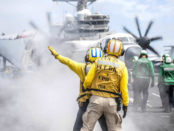 Chief Aviation Boatswain’s Mate signals a C-2A Greyhound on the flight deck of the aircraft carrier USS Ronald Reagan.