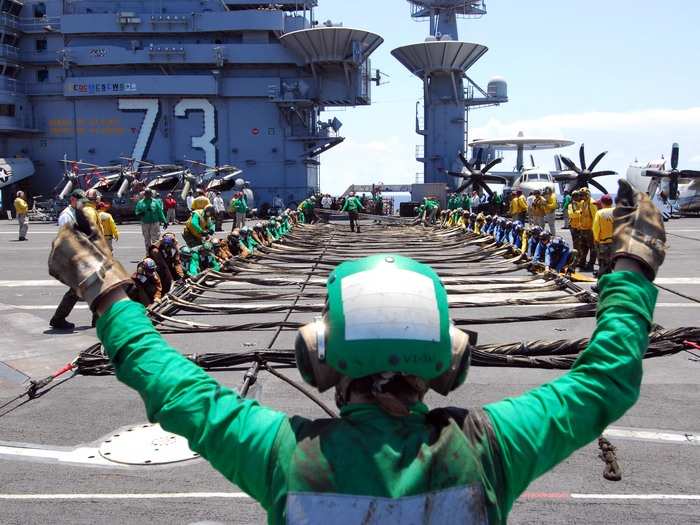 Sailor signals for Sailors to set up the aircraft barricade during a drill aboard USS George Washington.