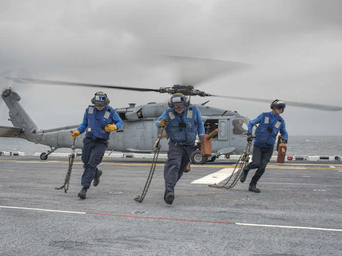 Sailors conduct a chock and chain evolution with an SH-60 Sea Hawk aboard USS Wasp.