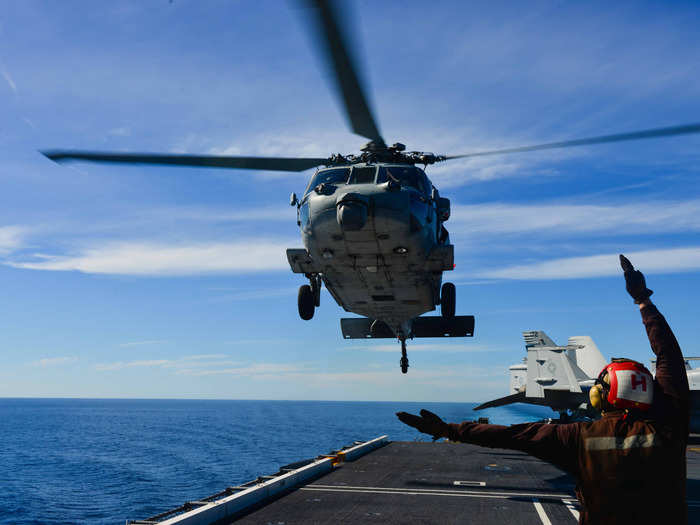 An Airman directs an MH-60S Sea Hawk helicopter on the flight deck of aircraft carrier USS John C. Stennis.