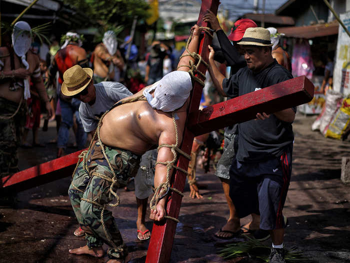 A devotee is helped up during The Way of The Cross in the Philippines.