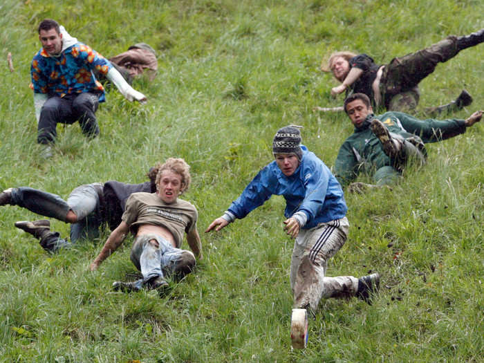 During cheese rolling, a large cheese wheel is rolled down a steep hill, and competitors race after it. The first person to make it down the hill wins the cheese.