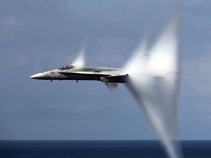 An F/A-18C Hornet assigned to Strike Fighter Squadron 113 breaks the sound barrier during an air power demonstration over the Nimitz-class aircraft carrier USS Carl Vinson.