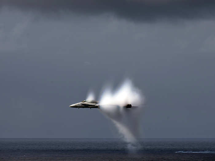 An F/A-18C Hornet assigned to Strike Fighter Squadron 113 breaks the sound barrier during an air power demonstration over the Nimitz-class aircraft carrier USS Carl Vinson.