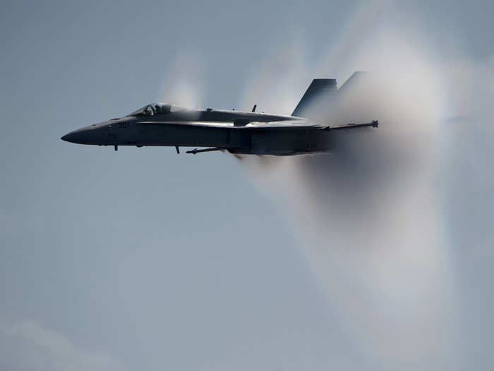 An F/A-18C Hornet assigned to Strike Fighter Squadron 113 breaks the sound barrier alongside the Nimitz-class aircraft carrier USS Carl Vinson during an air power demonstration.