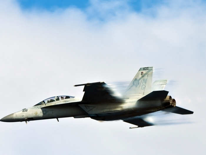 An F/A-18F Super Hornet from the Black Aces of Strike Fighter Squadron 41 breaks the sound barrier during an air power demonstration for participants of a tiger cruise aboard the Nimitz-class aircraft carrier USS John C. Stennis.