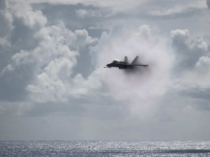 An F/A-18C Hornet assigned to Strike Fighter Squadron 113 breaks the sound barrier over the Nimitz-class aircraft carrier USS Carl Vinson during an air power demonstration.