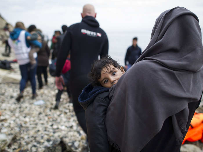 A Syrian woman carries her daughter after arriving on the beach, crossing the sea from Turkey to Lesbos, some 5 kilometers (3.1 miles) south of the capital of the island, Mytelene, on March 9, 2016, in Mytelene, Greece.