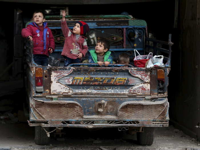 A boy gestures as he sits with others on a pickup truck in the rebel held Douma neighborhood of Damascus.