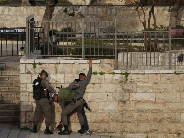 Israeli border policemen perform a security search on a Palestinian youth near the Damascus Gate outside of Jerusalem