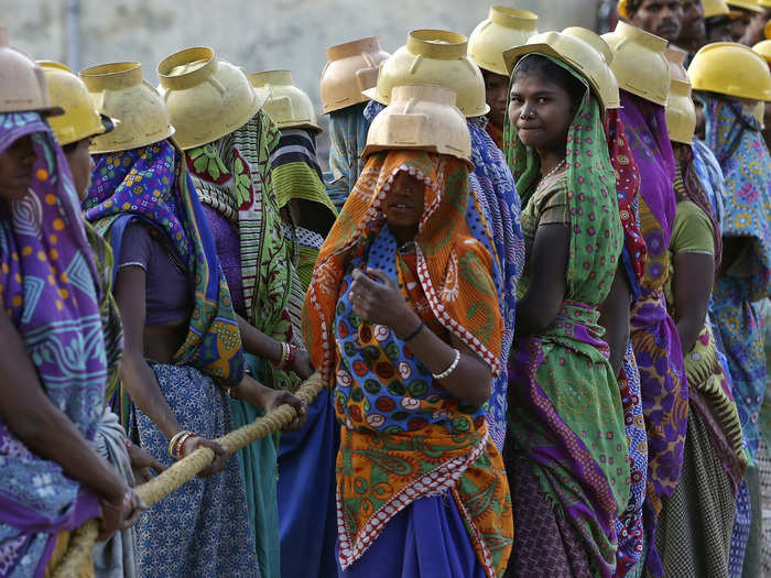 Female laborers wearing helmets take a break from laying underground electricity cables in Ahmedabad, India.