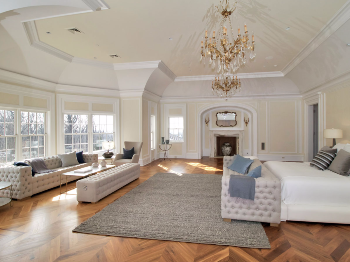 The master bedroom now features a plush King-sized bed and a seating area near the window that overlooks the pool and tennis court outside. A neutral color scheme incorporates whites and light colors helps allow the natural light flow through the open and airy space.