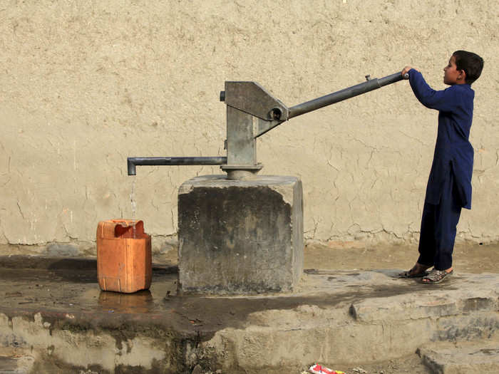 In Peshawar, Pakistan, women and children draw drinking water from a well using a hand pump.