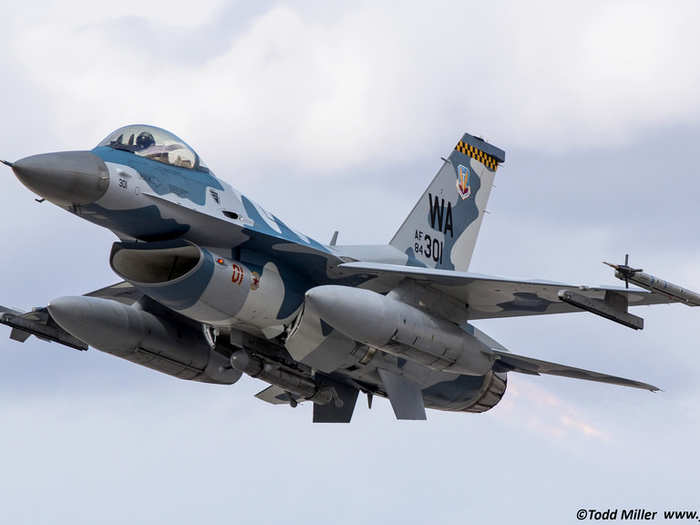 An F-16 Fighting Falcon flies with naval camouflage.