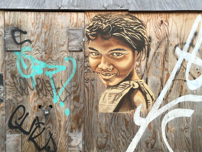 A graffiti portrait by LMNOPI on a wooden surface has a more subtle approach, the colors blending seamlessly into the wall.