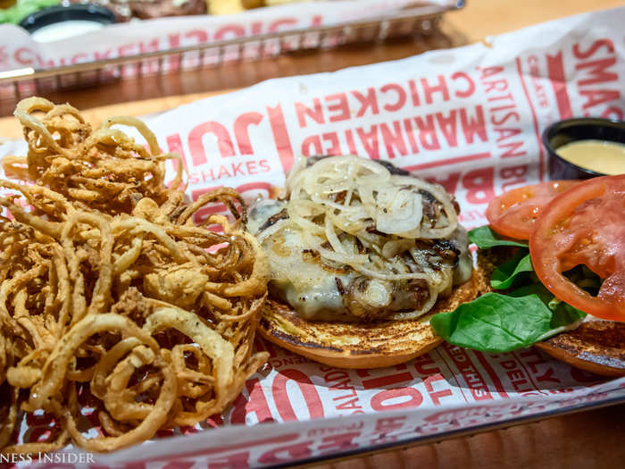 We ordered the "New Yorker" burger, topped with grilled onions, cheddar cheese, spinach, tomato, and peppercorn aioli on a brioche bun, with a side of onion rings ...