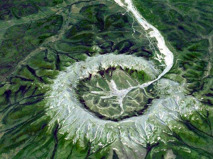 The perfectly circular intrusion of Kondyor Massif in Russia formed when molten magma crystallized underneath the Earth then rose to the surface. A stream flows out of its center.