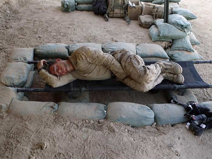 A U.S. Marine from 1st Battalion, 8th Marines sleeps on a stretcher in the shade at an outpost in Kunjak, in southern Afghanistan