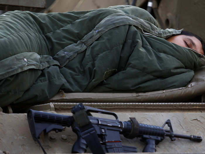 An Israeli soldier sleeps atop an Armoured Personnel Carrier (APC) at an Israeli Defence Forces (IDF) staging area in the central Gaza border November 21, 2012.