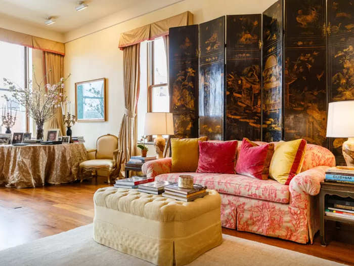 The decor is cozy and global, with Asian and French influences like this painted folding screen and the tufted ottoman.