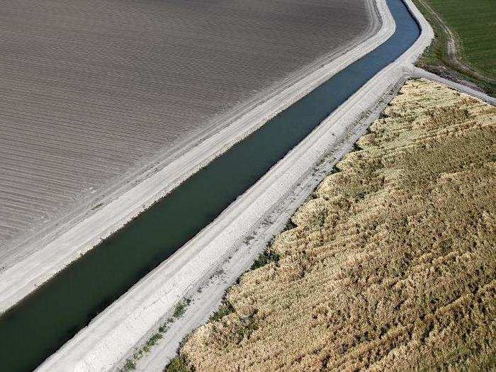 A canal runs through dried-up farm fields in Los Banos.