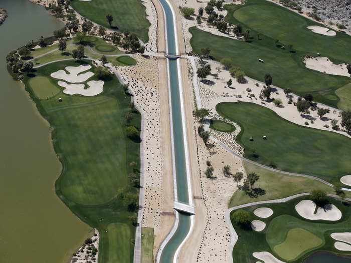 A dried-up canal runs through a lush green golf course in La Quinta.