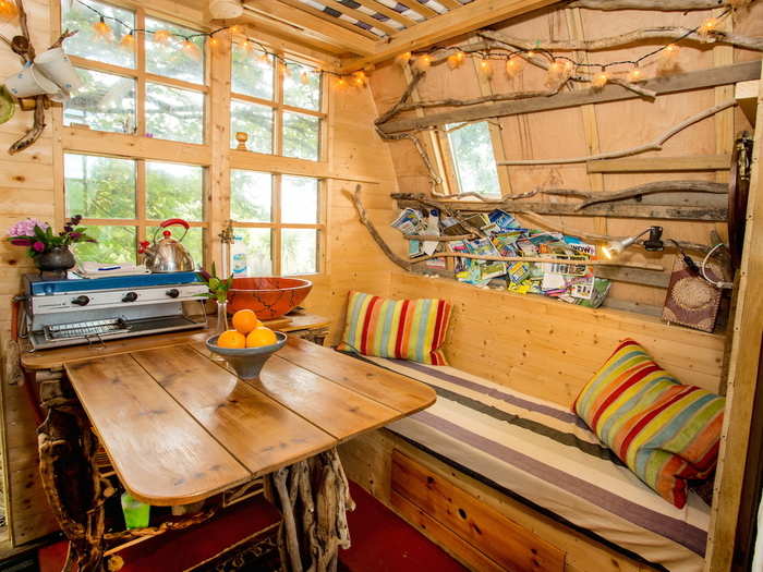 The living room is compact but the host has made clever use of the space to make it feel more spacious. For example, the tree twigs lining the walls double as a magazine rack.