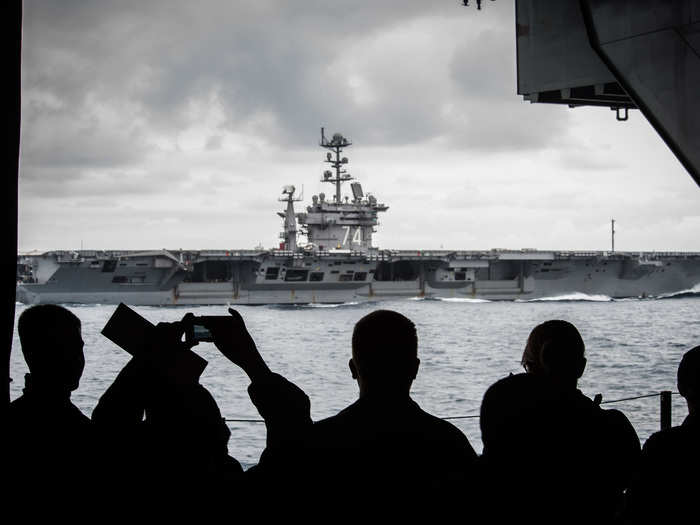 Sailors observe as the aircraft carrier USS John C. Stennis sails alongside the aircraft carrier USS Ronald Reagan.