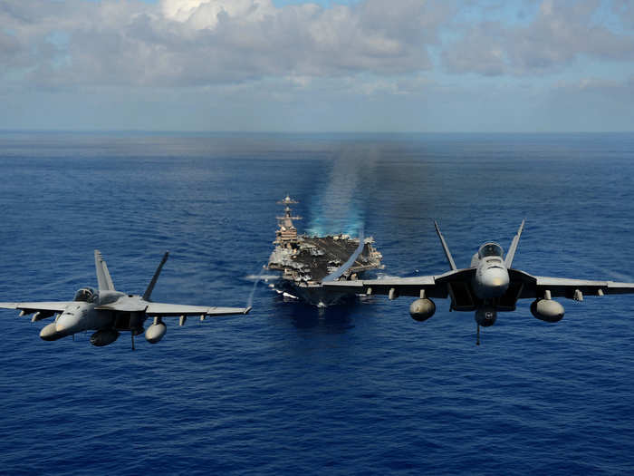 F/A-18 Hornets demonstrate air power over the aircraft carrier USS John C. Stennis (CVN 74).