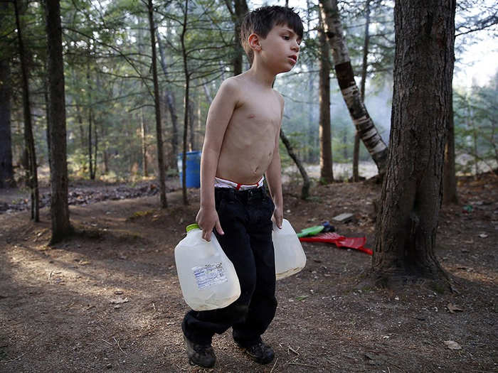 After moving into a campground, Strider struggles as he carries gallons of water filled from a spigot to the camper.