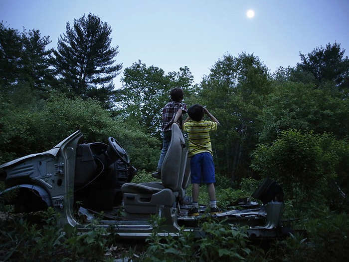 Often left to their own devices, Strider and Gallagher played on an abandoned Ford at twilight. Strider holds a broken automotive hose to his eyes like a pair of binoculars and asks, "What