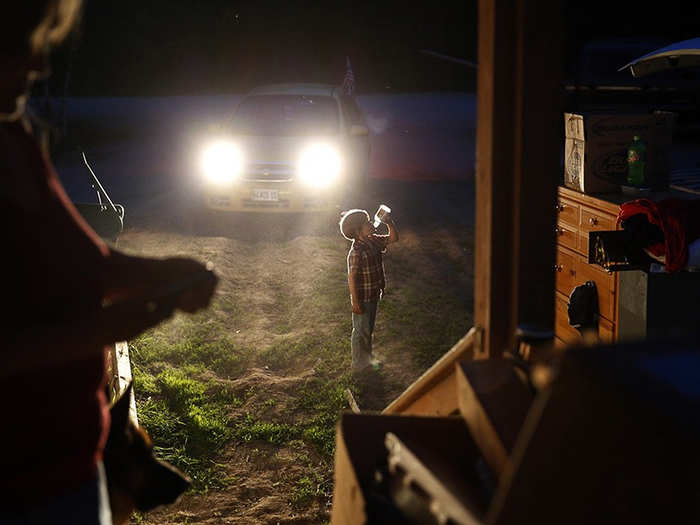 Gallagher cools off with a drink as Larry and Lanette scramble to pack by the light of their car headlights as the midnight eviction deadline inches closer. The landlord has cut the power and put locks on the electrical boxes in an attempt to force them off the property.